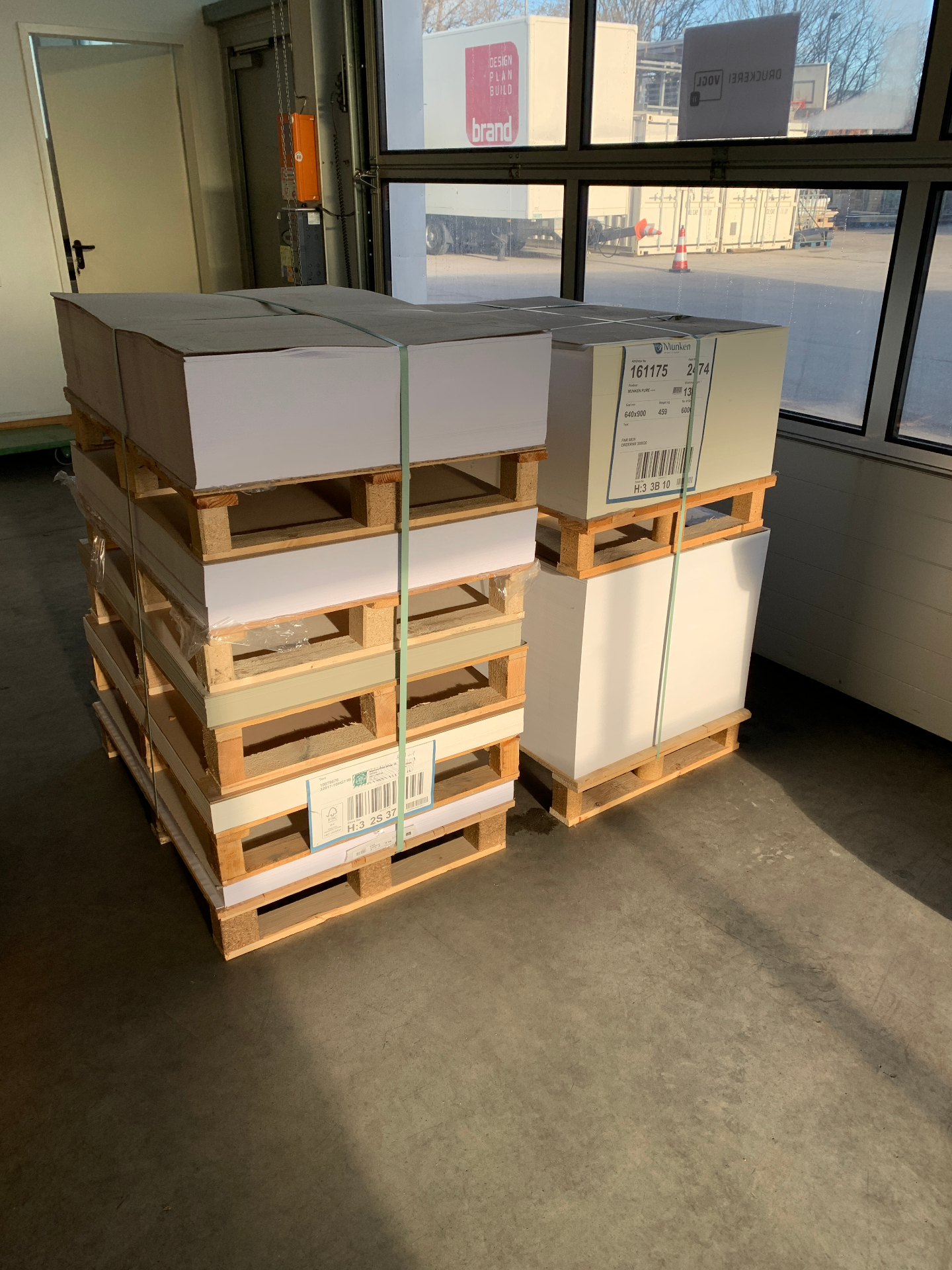 Gestapelte Paletten mit geretteten Papierbögen in der Druckerei